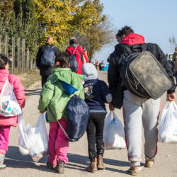 BERKASOVO, SERBIA - OCTOBER 31, 2015: Refugees walking carrying heavy bags on the Croatia Serbia border, between the cities of Bapska and Berkasovo on the Balkans Route, during the Refugee Crisis