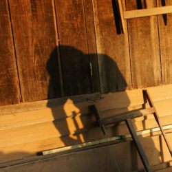 DALAT VIETNAM- JAN 24: Carpenter saw wood by power saw at home he working with concentration his shadow reflect on the wall of wooden house Viet Nam Jan 24 2014