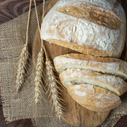 Fresh delicious crispy bread lies on a wooden background. Slices of sliced bread, linen napkin. Bakery concept, baking. Top view, flat lay